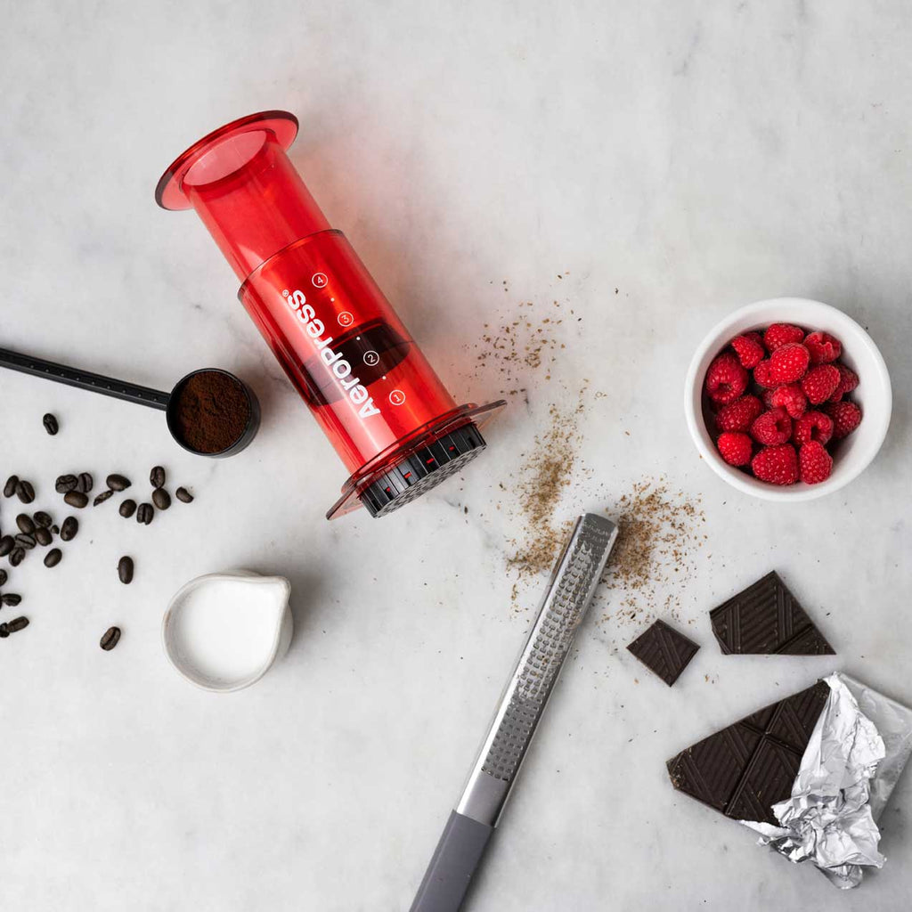 Red 10 oz AeroPress Clear Coffee Maker for manual brewing.
